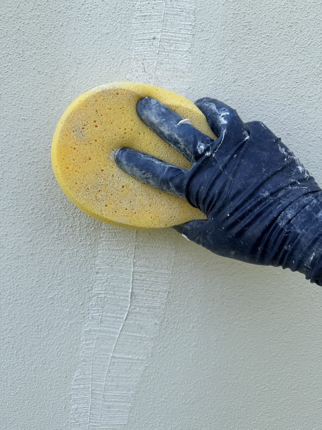 Gloved hand blending the patch with a yellow sponge